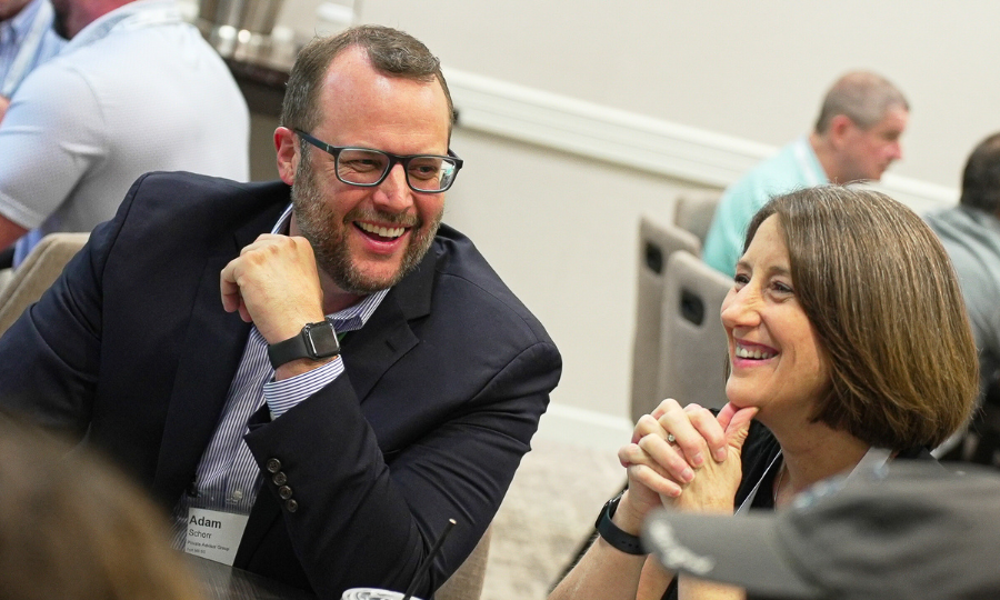 A smiling man and woman seated at a table, collaborating on investment management topics.