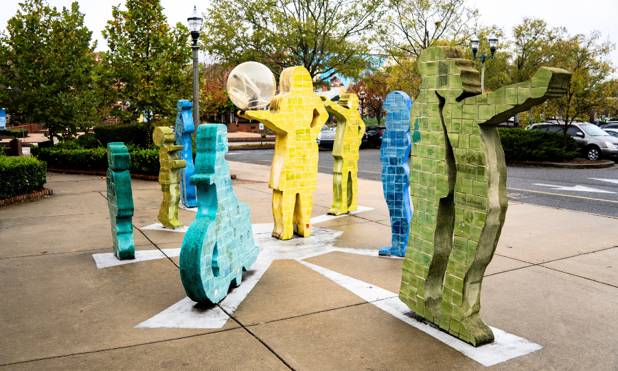 A vibrant collection of sculptures displayed on a sidewalk, showcasing various colors and artistic designs.